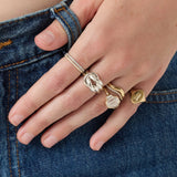 Hand wearing multiple gold rings on a denim background
