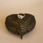 Decorative heart-shaped box with intricate designs on a beige background