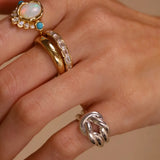 Hand wearing multiple rings with gemstones on a beige background