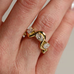 Gold ring with diamonds on a finger against a neutral background