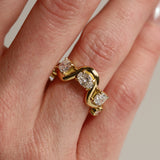 Gold ring with diamonds on a finger against a neutral background