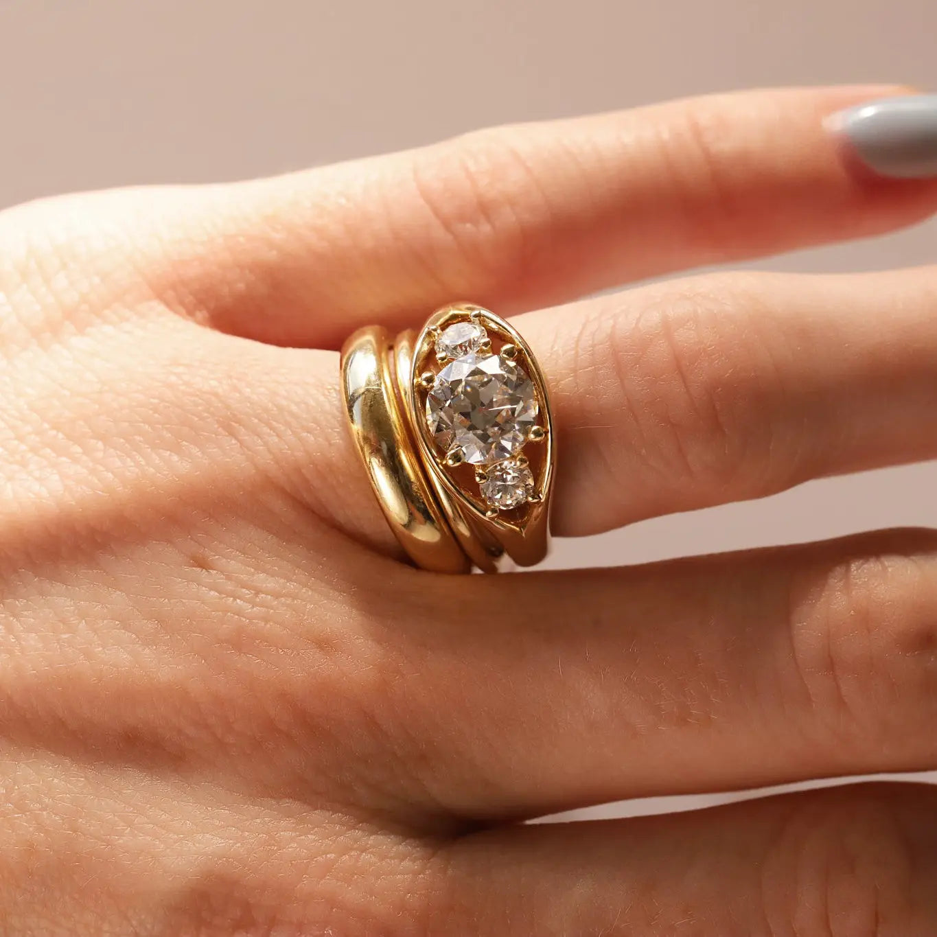 Close-up of hand wearing an open bombe ring with three round diamonds.