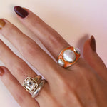Baroque Keshi Pearl and Burnt Orange Enamel Ring worn on the hand alongside a second ring