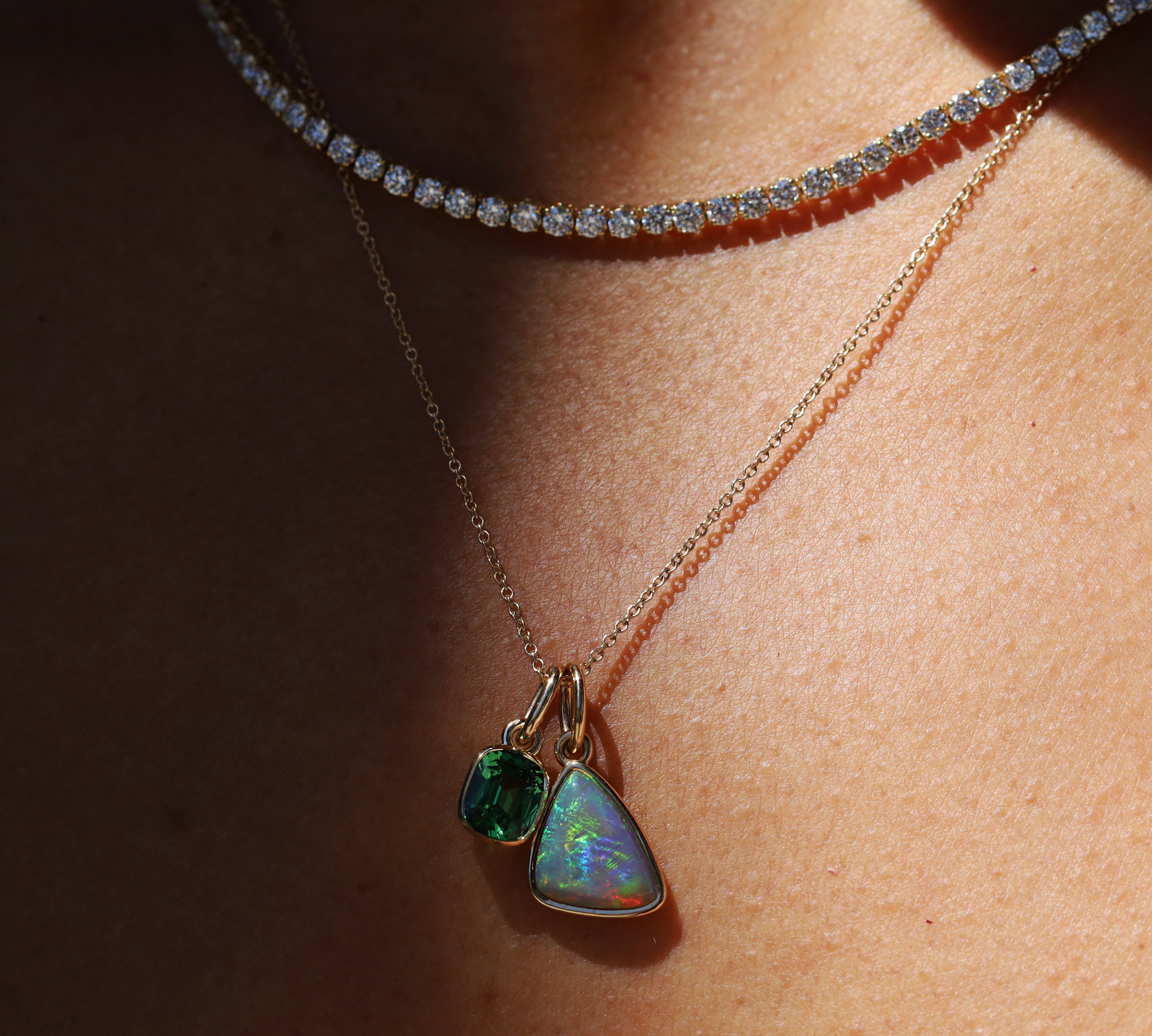 Necklace with two green gemstone pendants on a person's neck