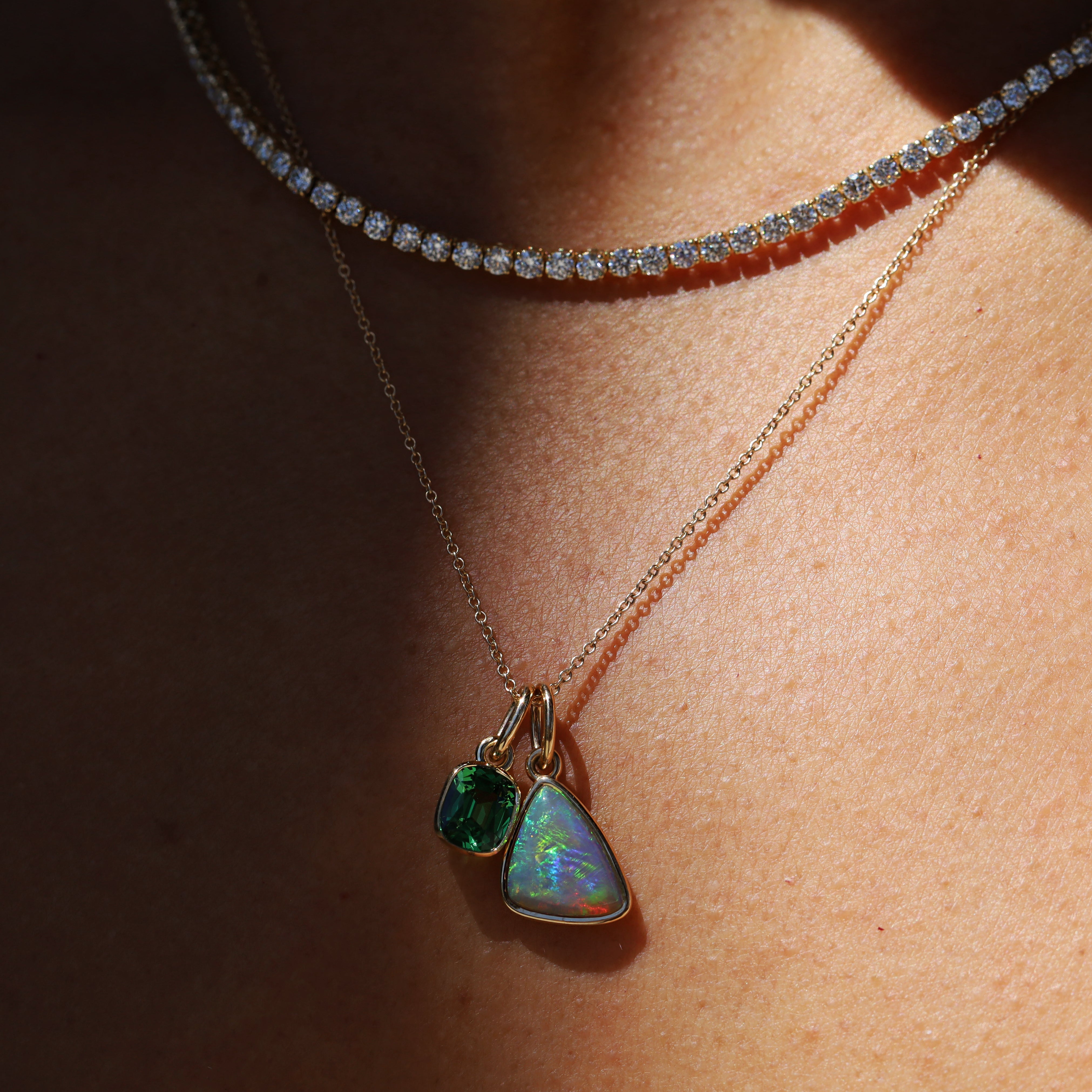 Necklace with two green gemstone pendants on a person's neck