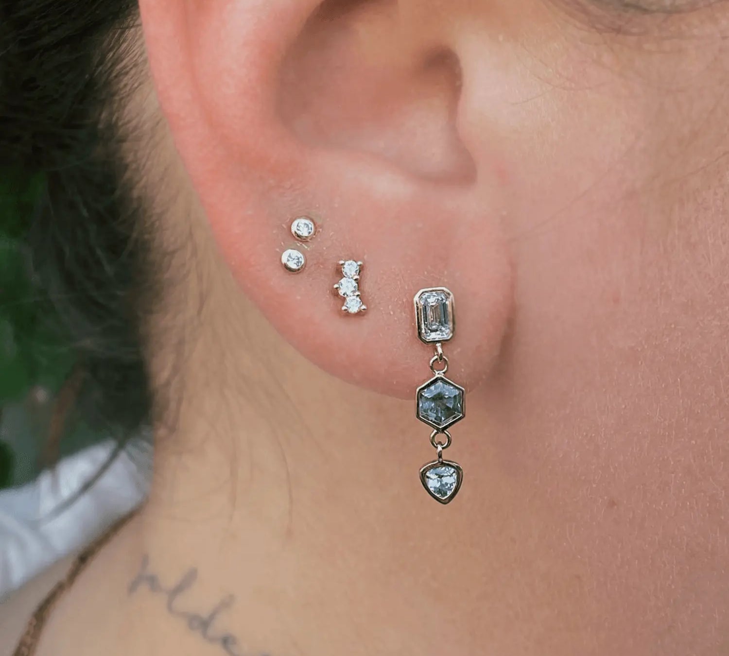 Image if ear with Marrow Fine white diamond stud earrings and Sapphire and Diamond Bezel Set Dangle Earrings on. There are three earrings on this single ear/