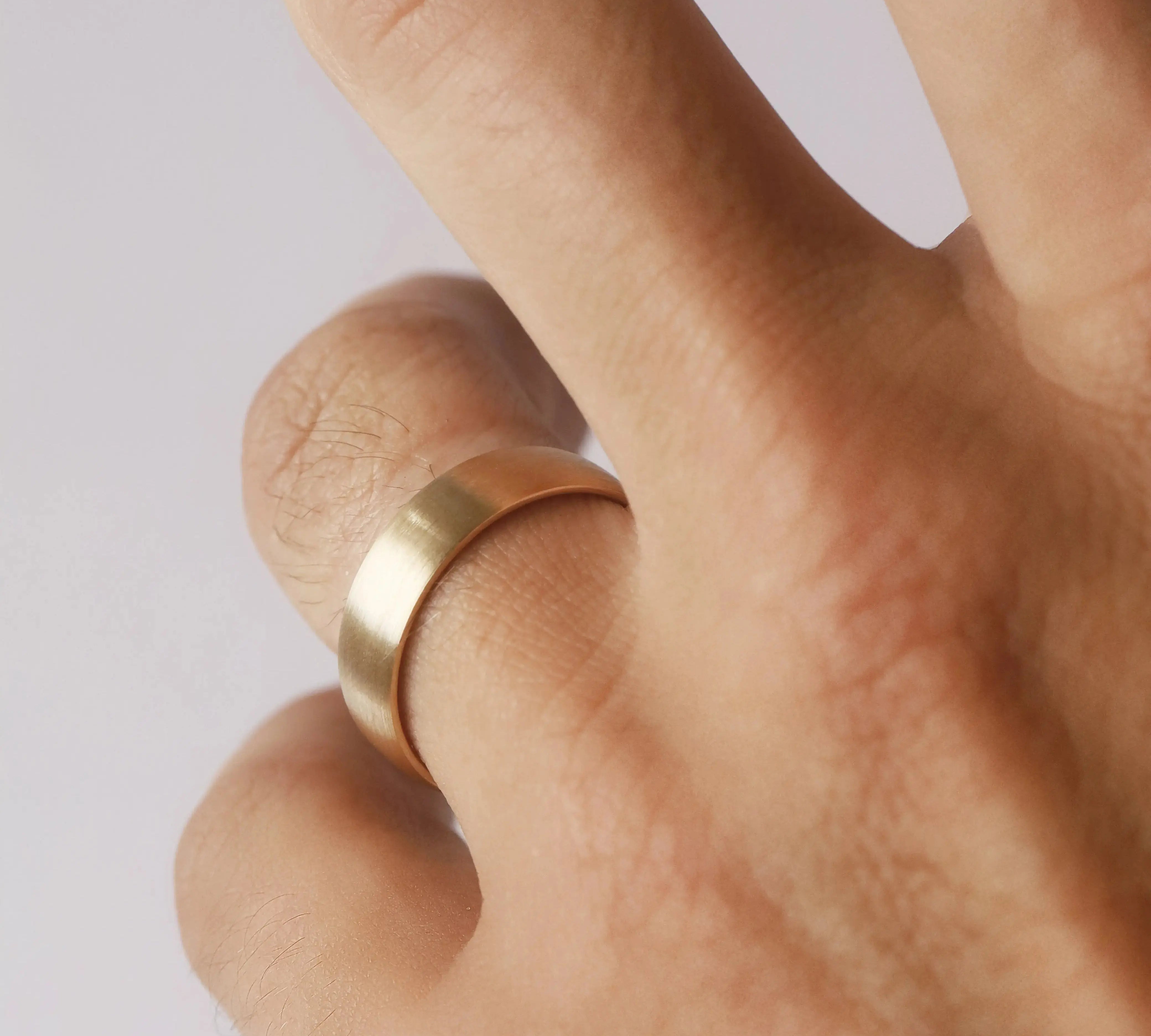 Gold ring on a finger against a light background