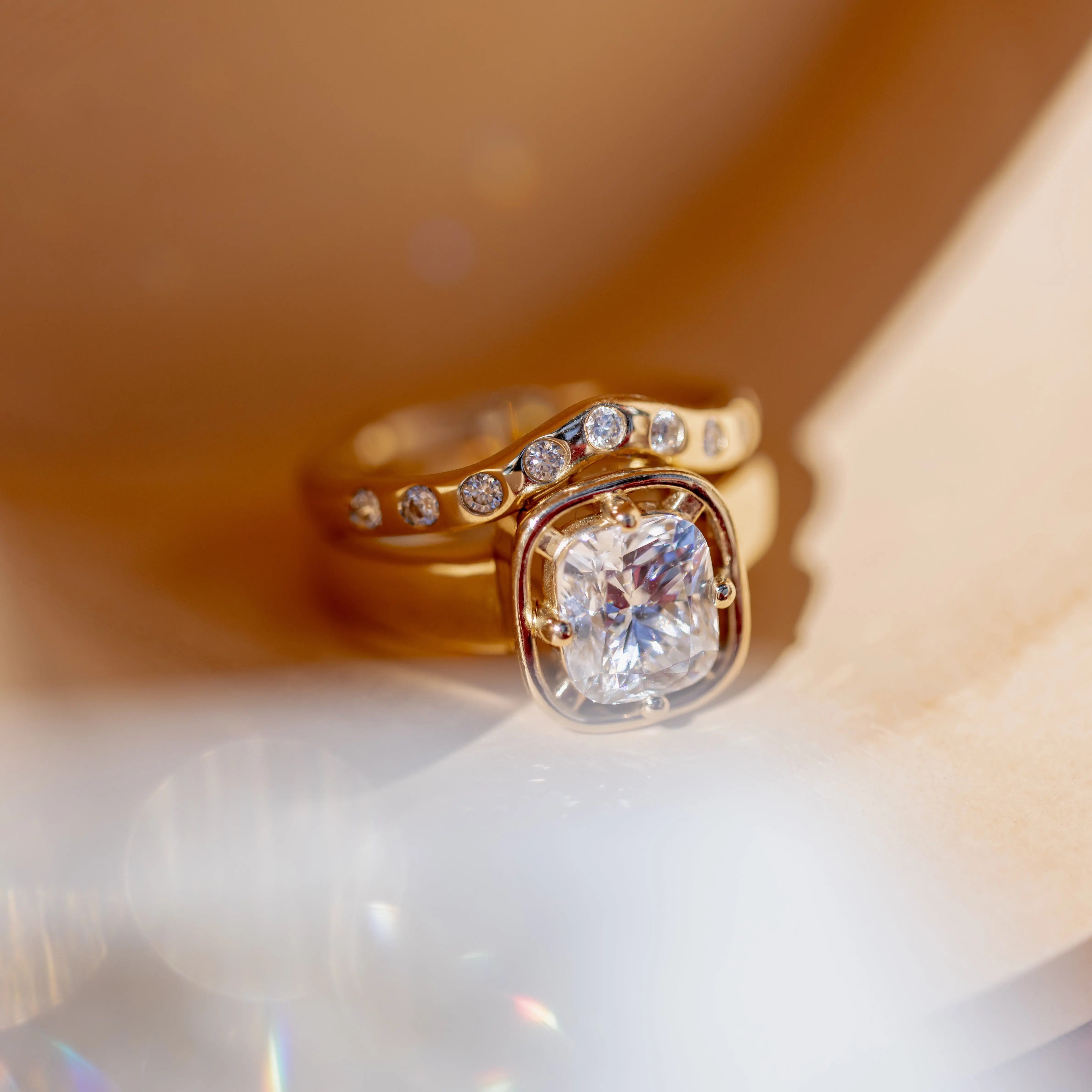 Gold ring with a large diamond and smaller diamonds on band against a soft focus background