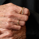 Close-up of an elderly hand wearing two gold rings with a dark background