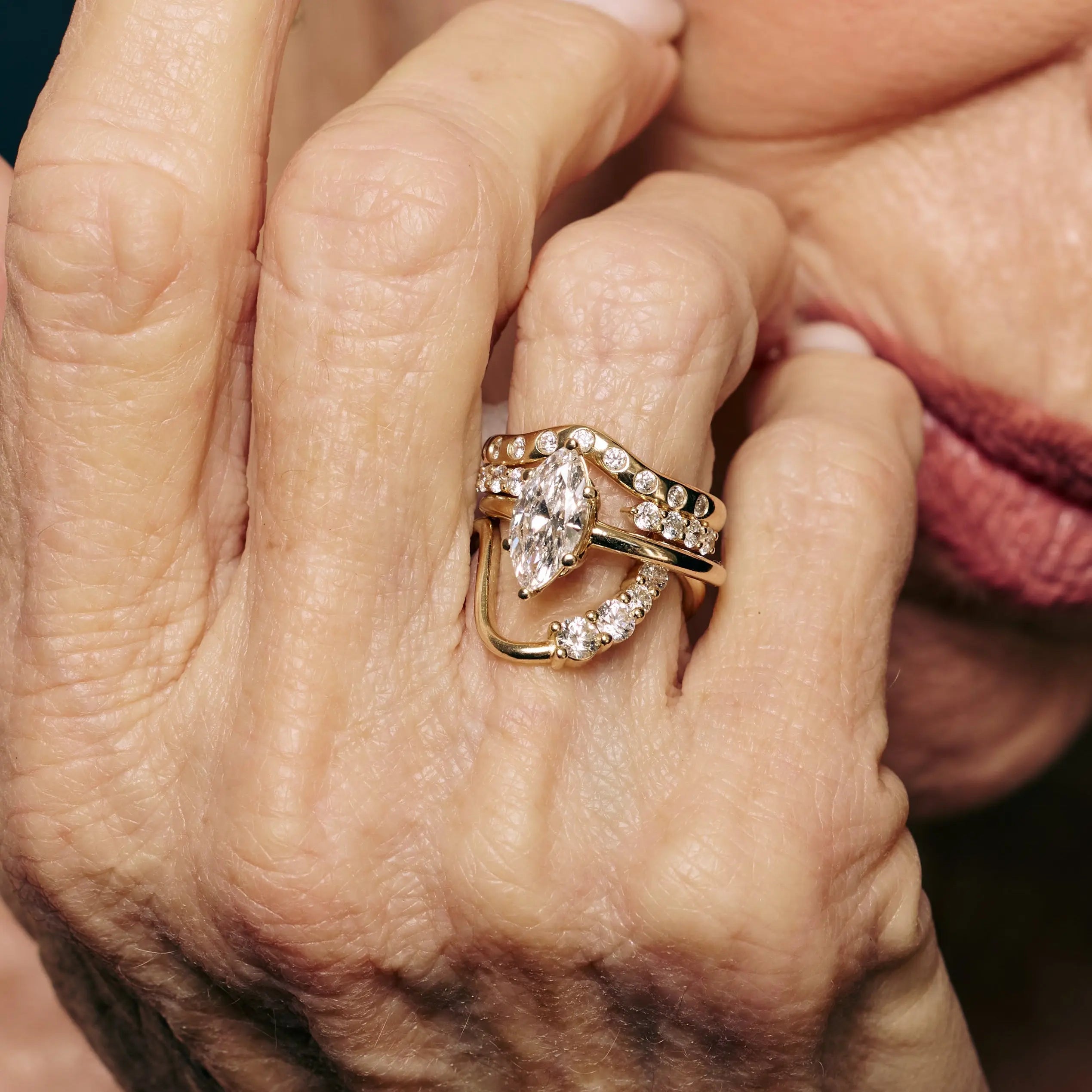 Diamond engagement ring and stacking bands on a silver-haired model's hand