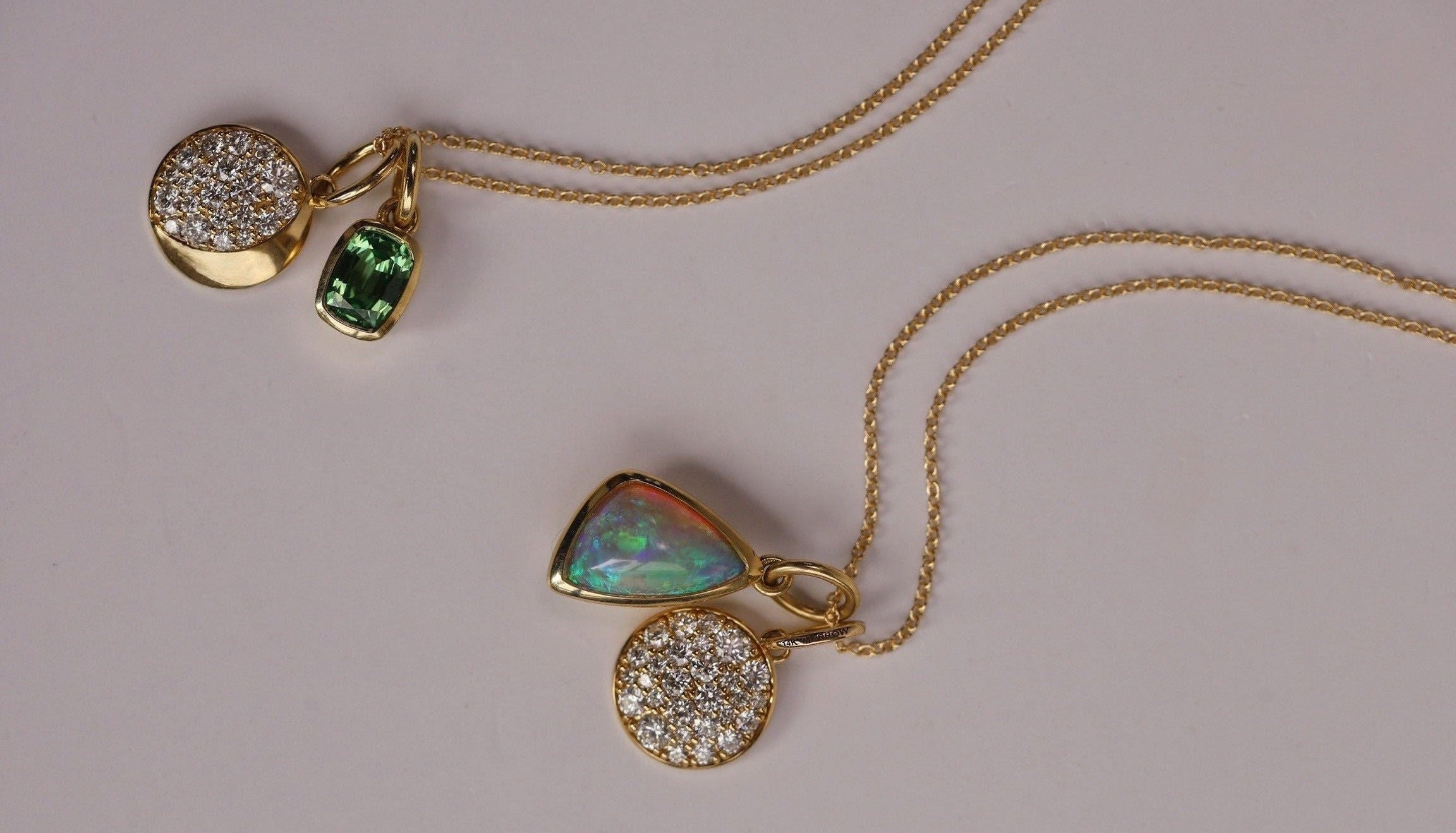 Gold necklace with pendant featuring opal and gemstones on a gray background