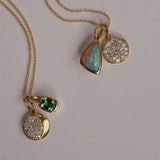 Gold necklace with three pendant charms on a light gray background