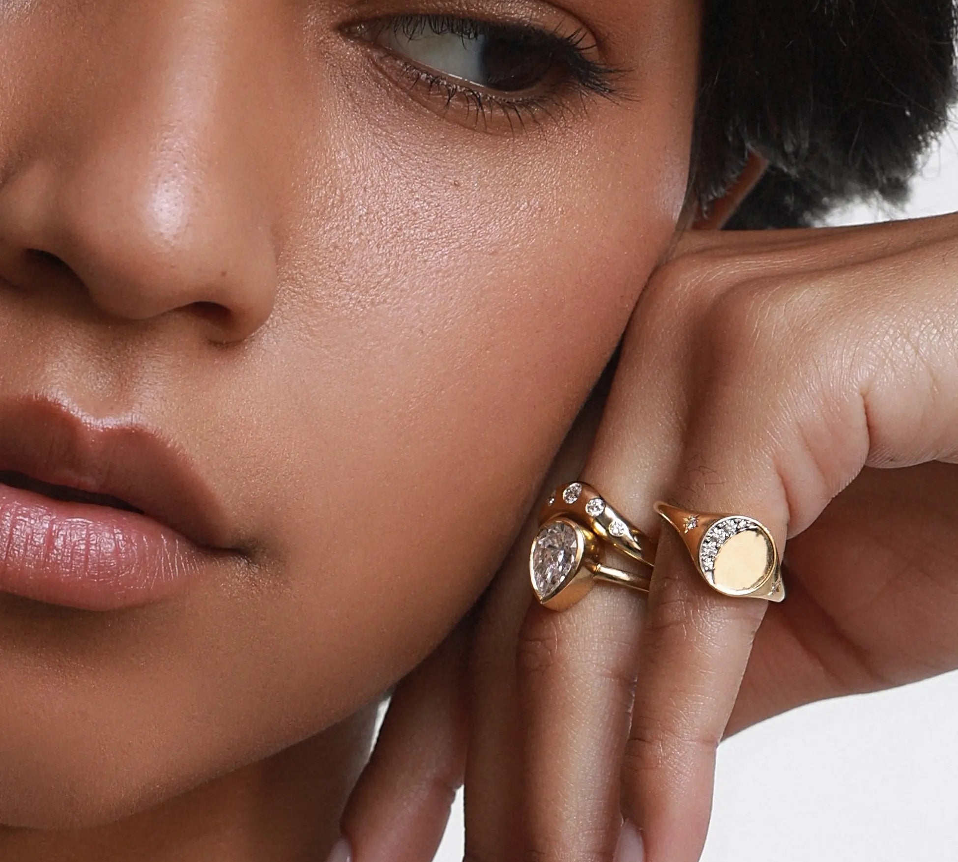 Close up of woman resting hand against her face, spotlighting the Crescent Moon Signet on her pinky ring