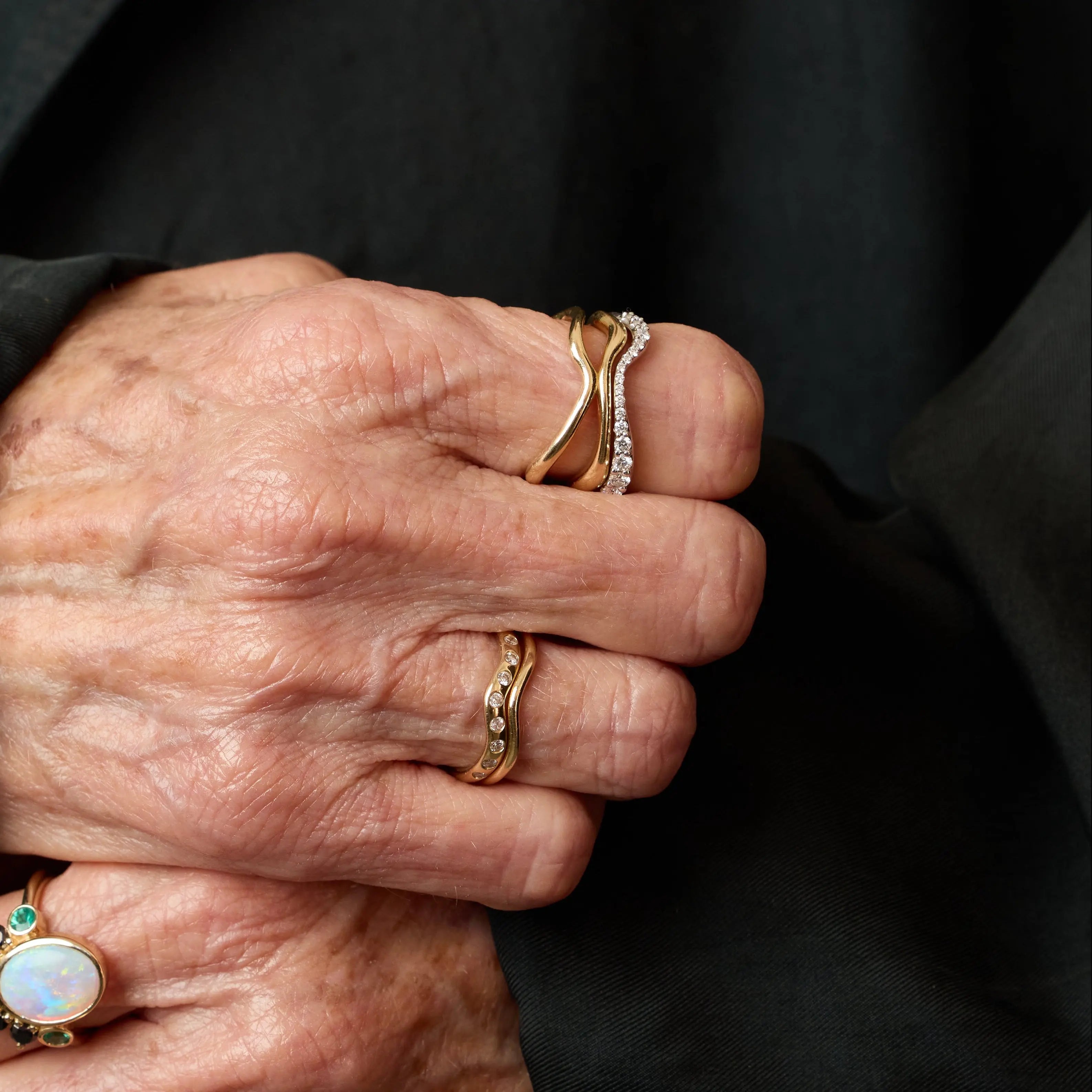 Close-up of hands with multiple rings on a black background