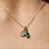 Necklace with two charms, one green and one clear, on a person's neck.