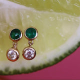 Gold earrings with green and diamond gemstones on a lime background