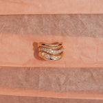 Gold ring with diamonds on a pink textured background