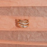 Gold ring with diamonds on a pink textured background