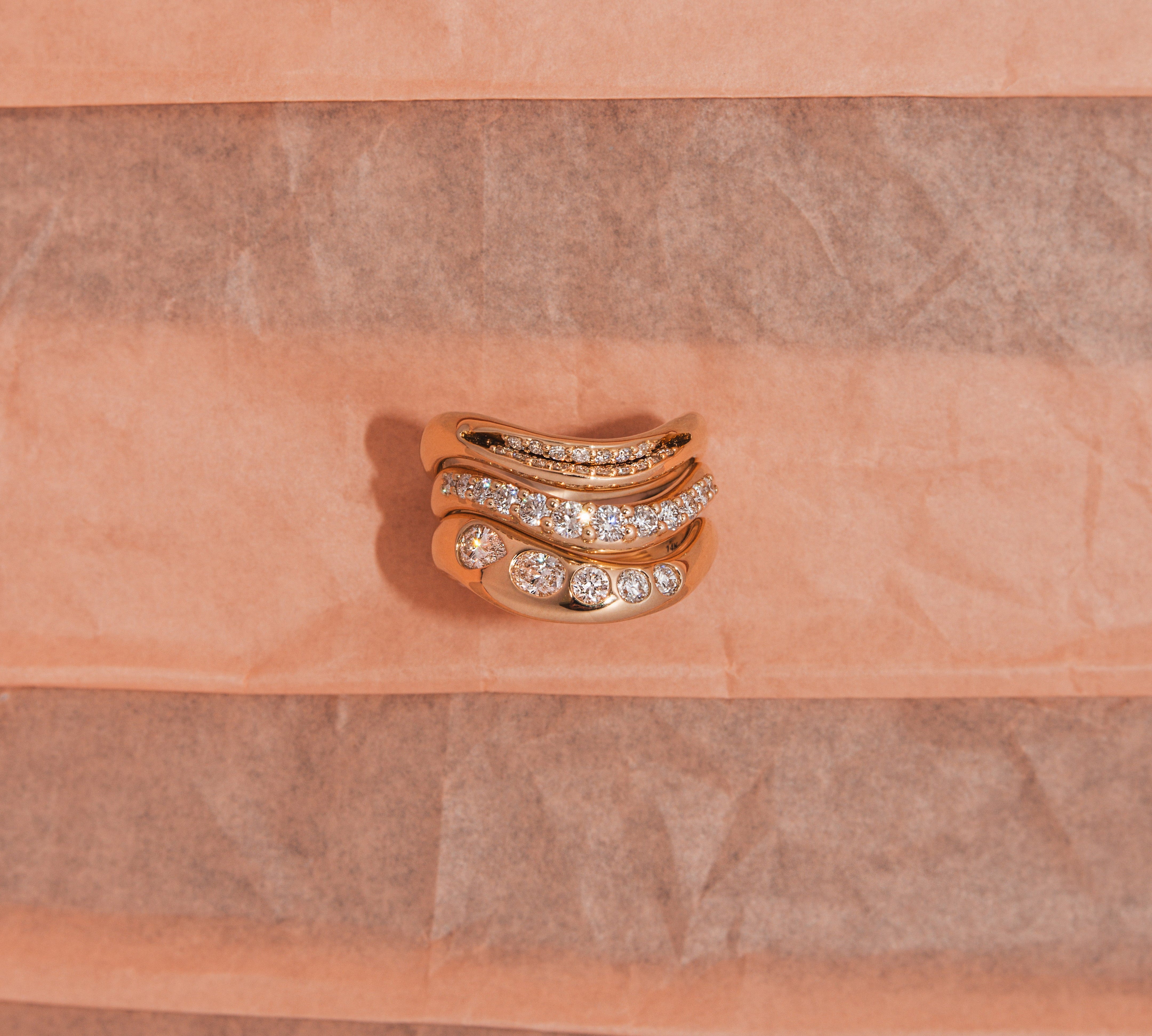 Gold ring with diamonds on a pink textured background