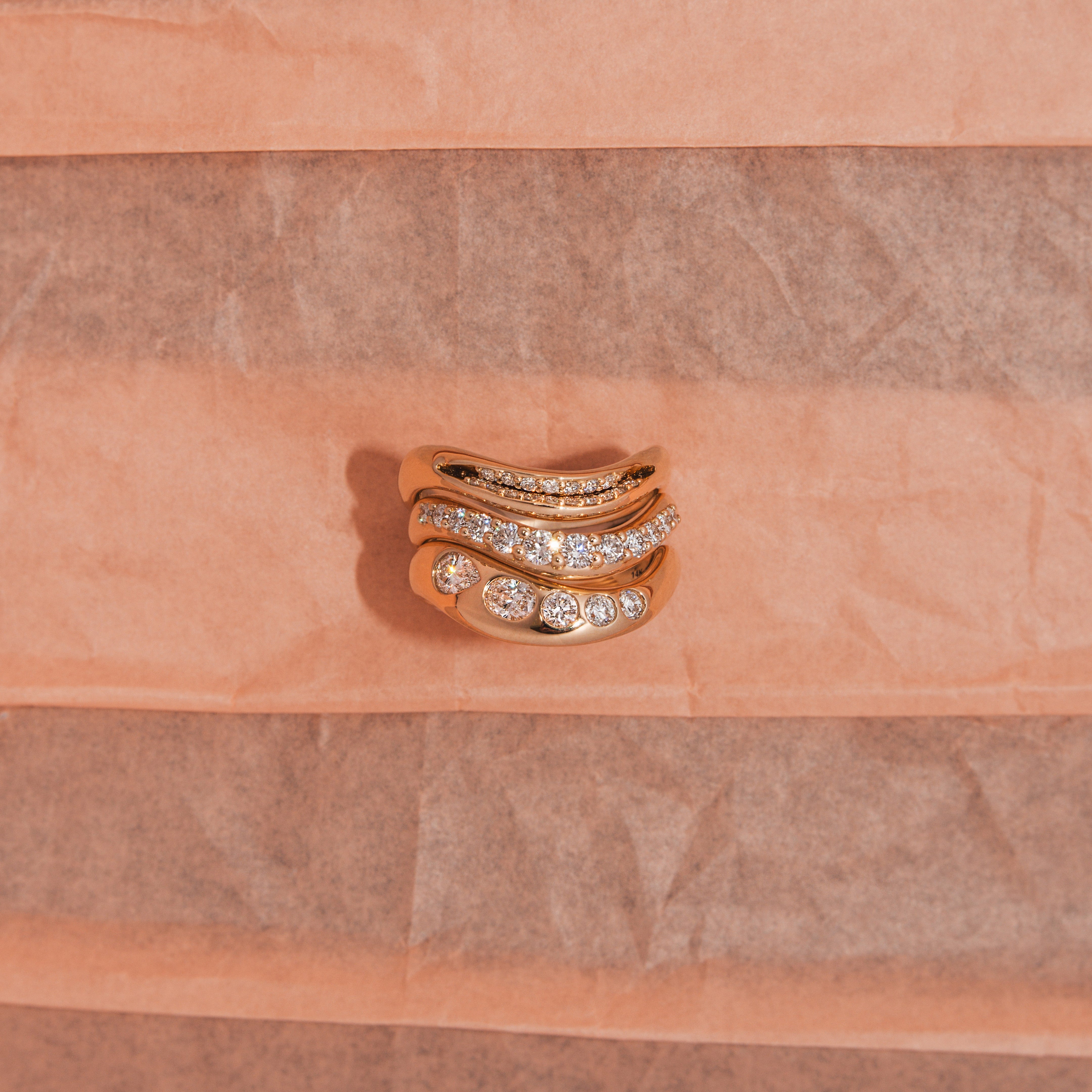 Gold ring with diamonds on a pink textured background