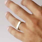 Hand wearing a gold ring on a light background