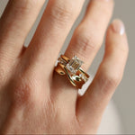 Gold ring with a diamond on a hand against a neutral background