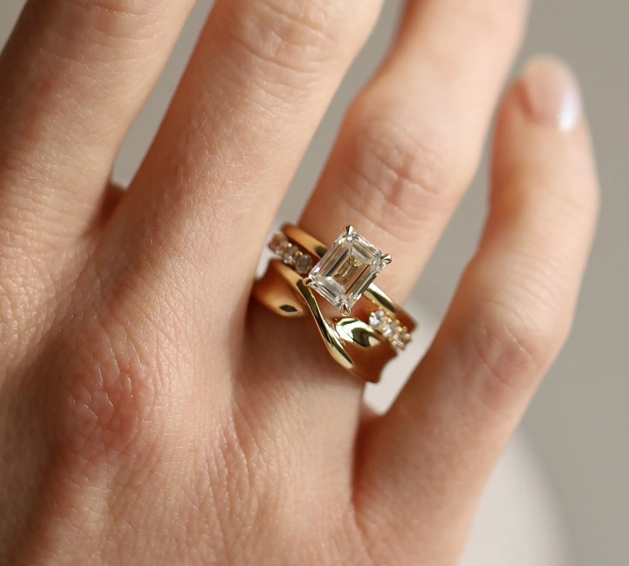 Gold ring with a diamond on a hand against a neutral background