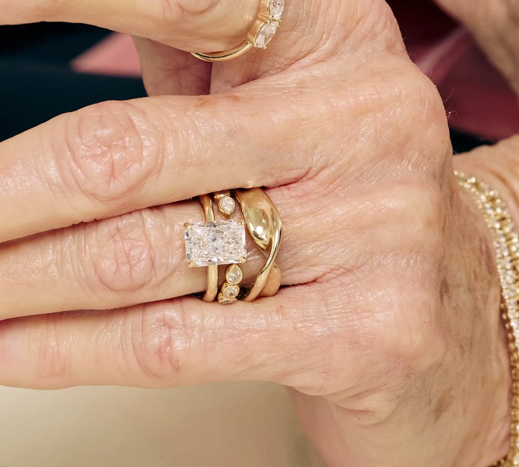 Close-up of a hand wearing multiple gold rings with diamond accents.