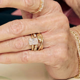 Close-up of a hand wearing multiple gold rings with diamond accents.