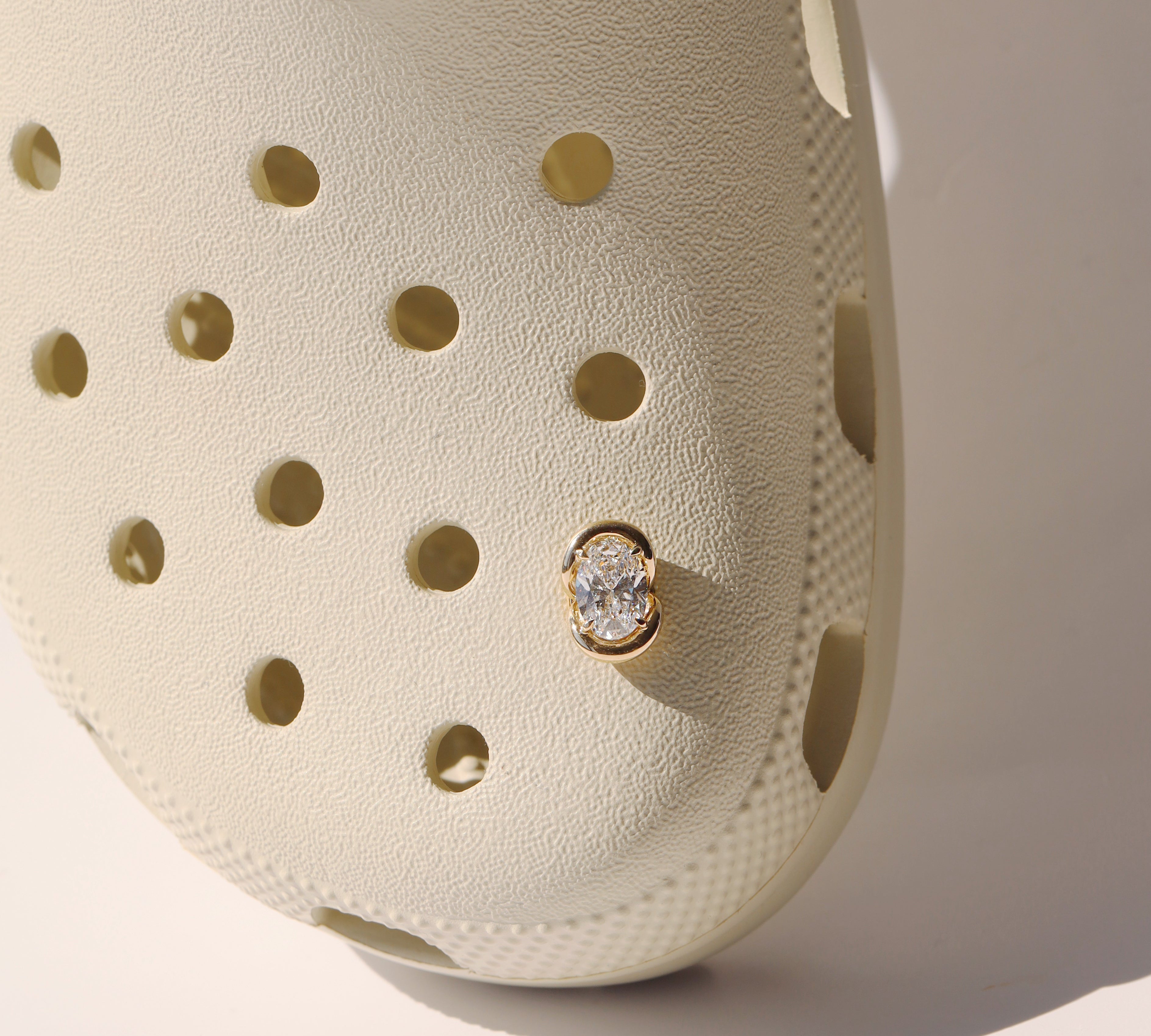 Beige clog shoe with a diamond charm on a light background