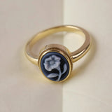 Gold ring with blue flower carving against a white backgound.