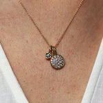 Gold necklace with two pendants on a person wearing a white top.