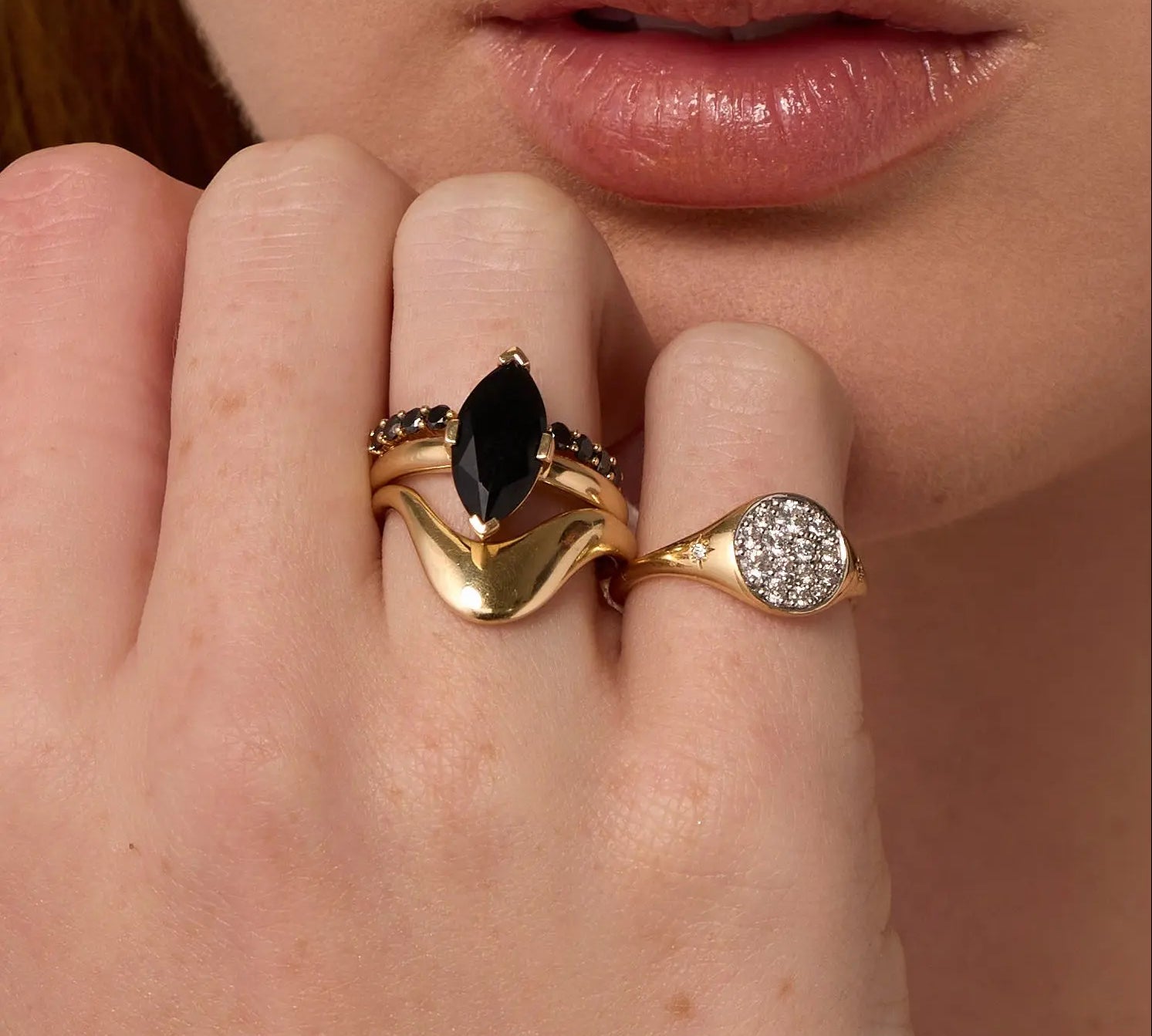 Close up of woman resting hand against her chin, highlighting multiple Marrow Fine rings styled and stacked together