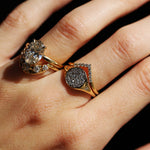 Gold ring with diamond accents on a hand against a dark background