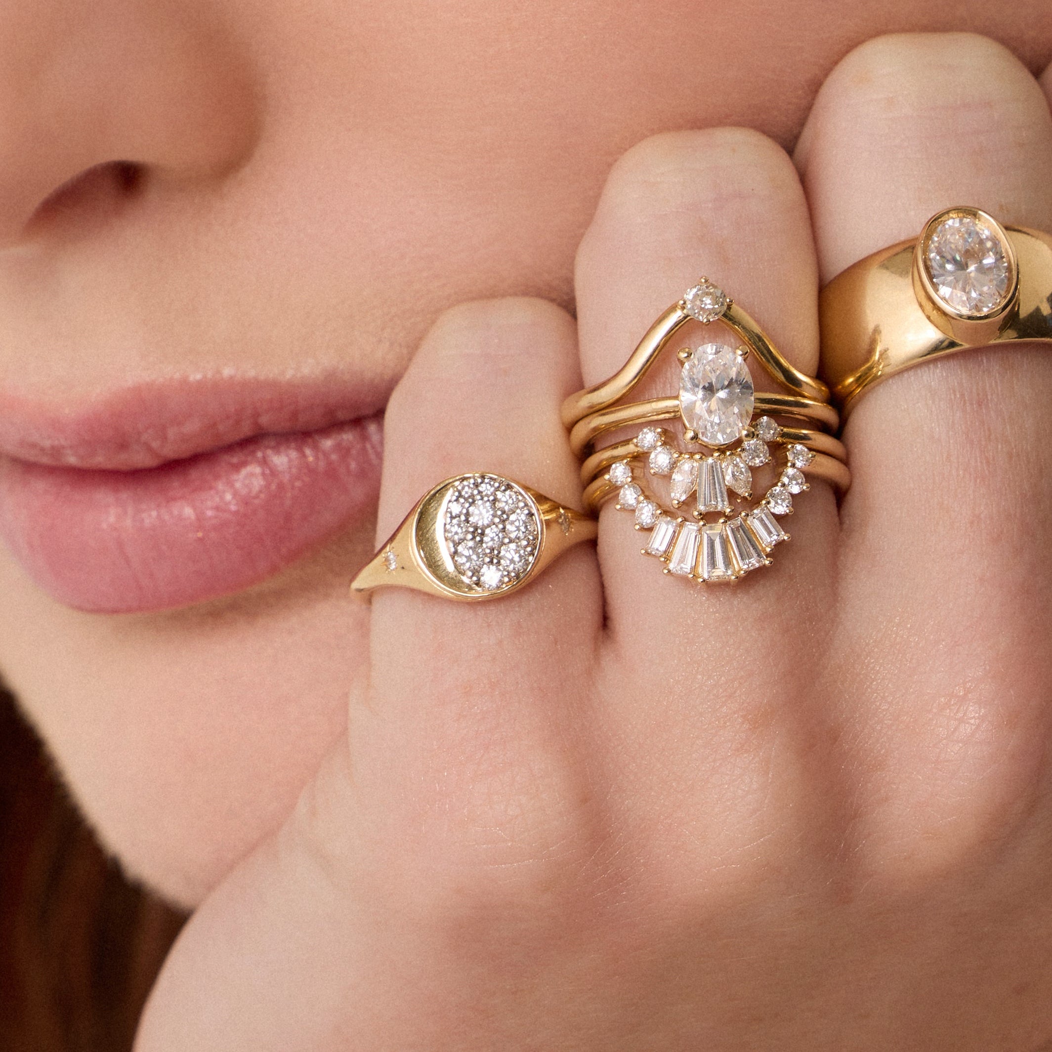Close up of woman resting hand agains her chin, highlighting multiple Marrow Fine diamond rings
