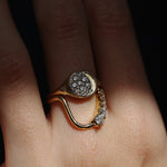 Gold ring with diamond accents on a finger against a dark background