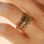 close up of woman's hand with gold MAMA ring and another yellow gold and diamond band