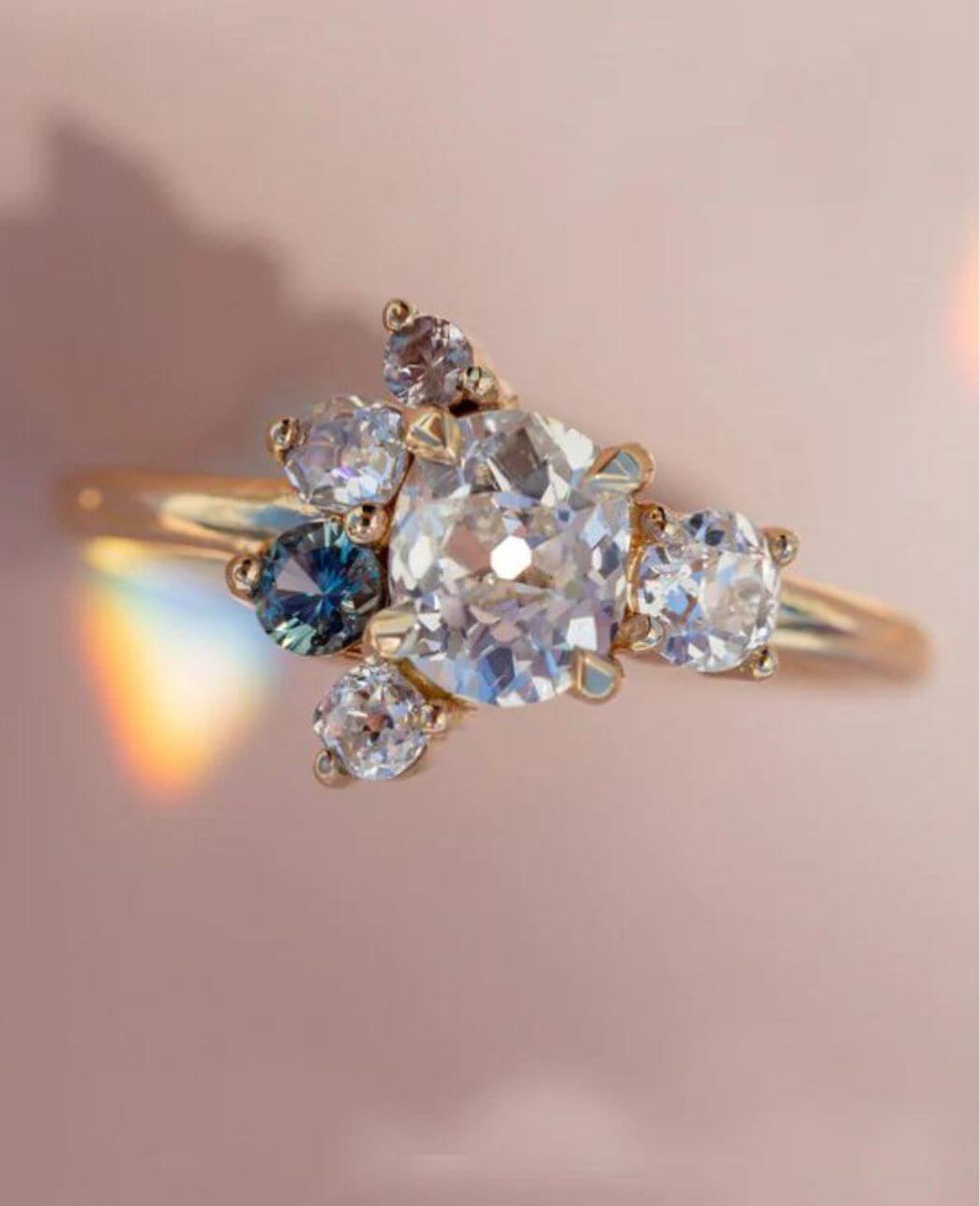 flat lay image of an heirloom rework cluster ring, featuring diamonds and sapphires