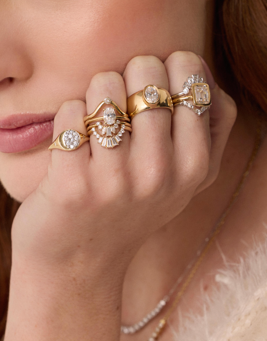 Close-up of a hand wearing multiple gold and diamond rings.