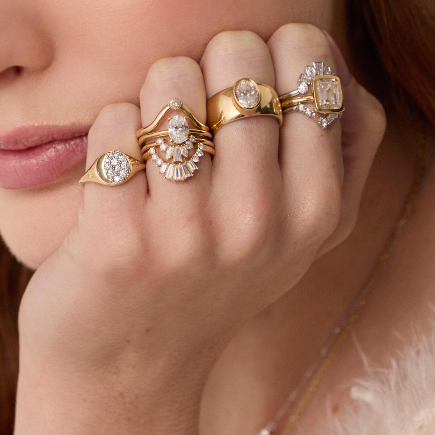 Close-up of a hand wearing multiple gold and diamond rings.