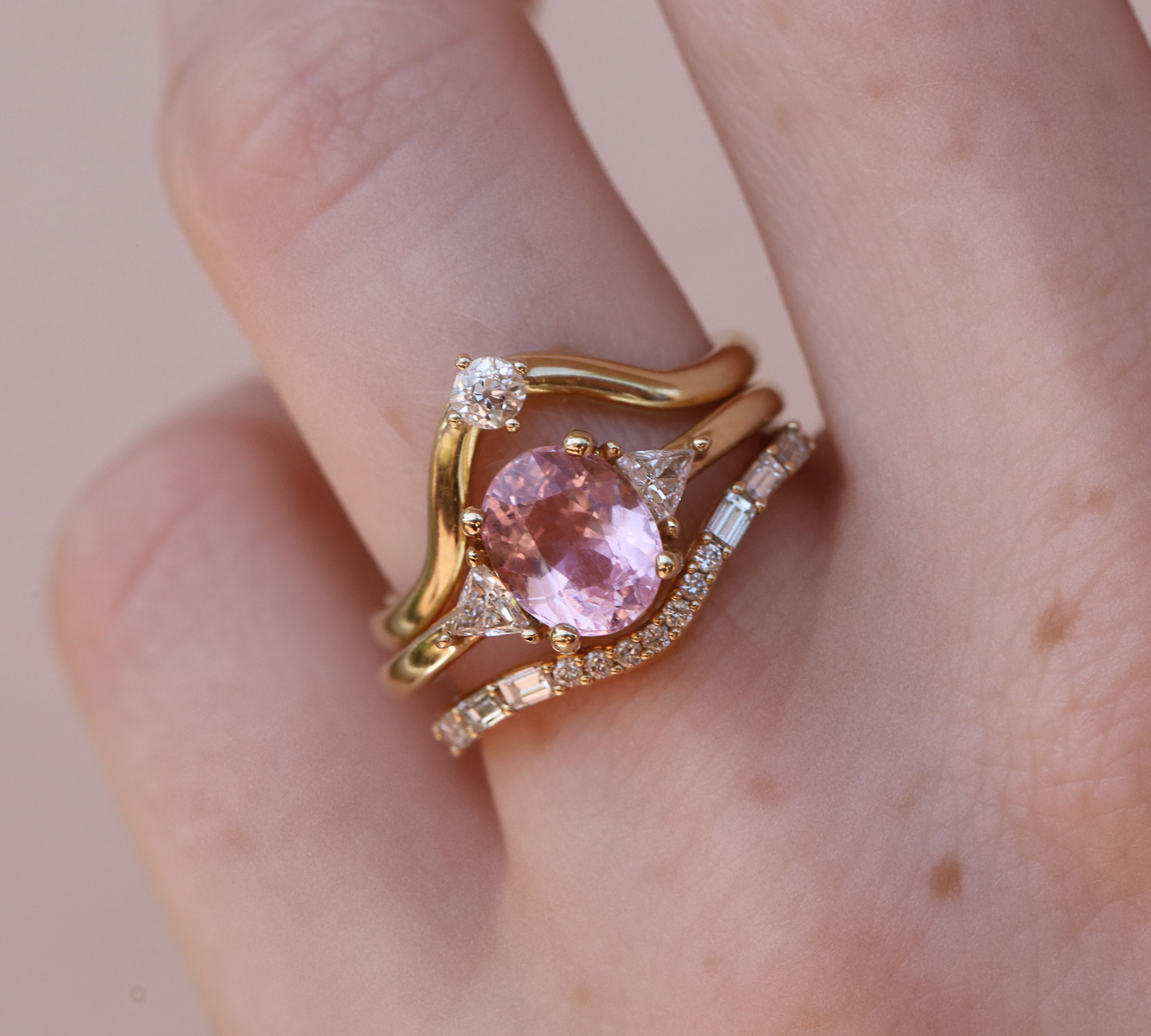 oval pink tourmaline ring with triangle side stones stacked with diamond bands