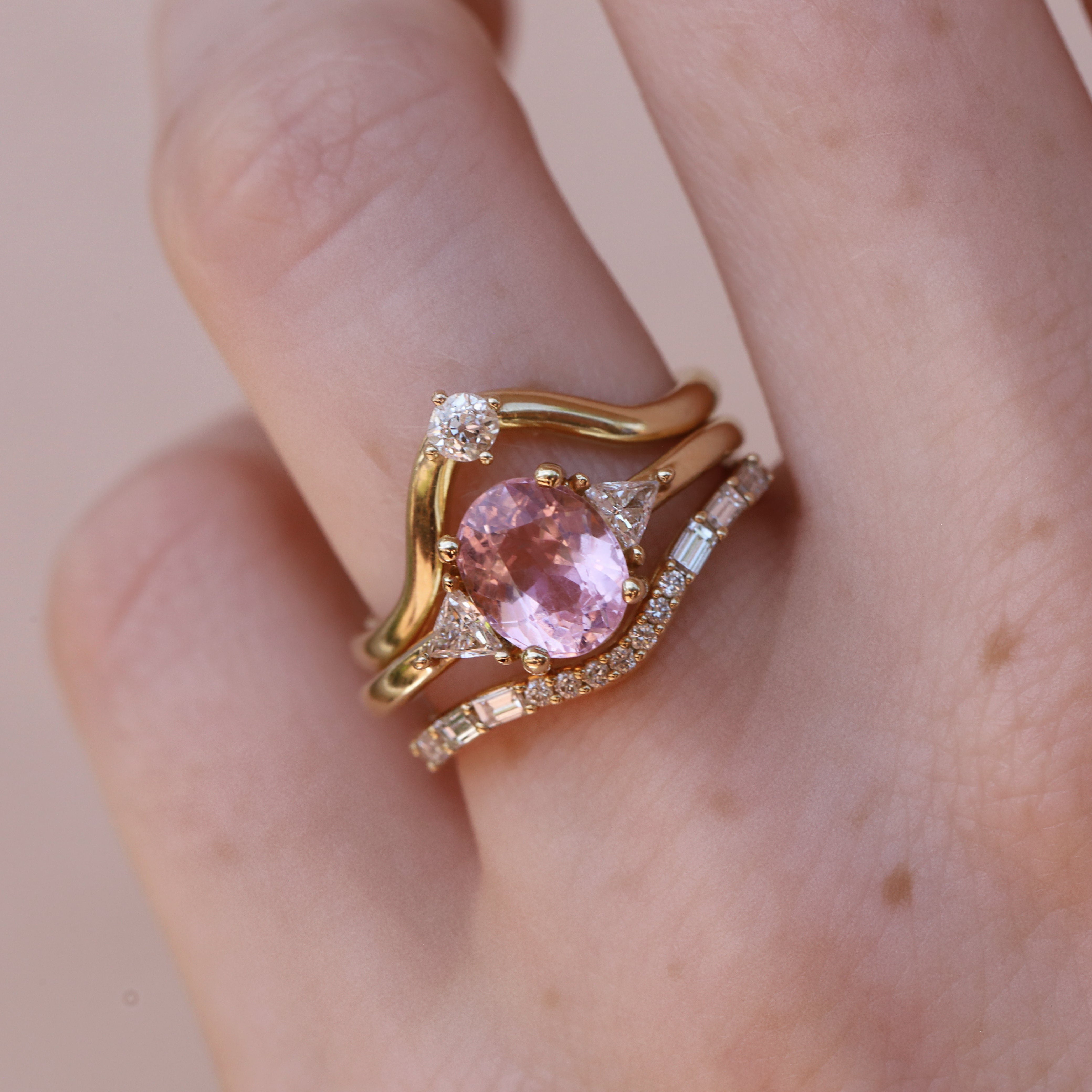 oval pink tourmaline ring with triangle side stones stacked with diamond bands