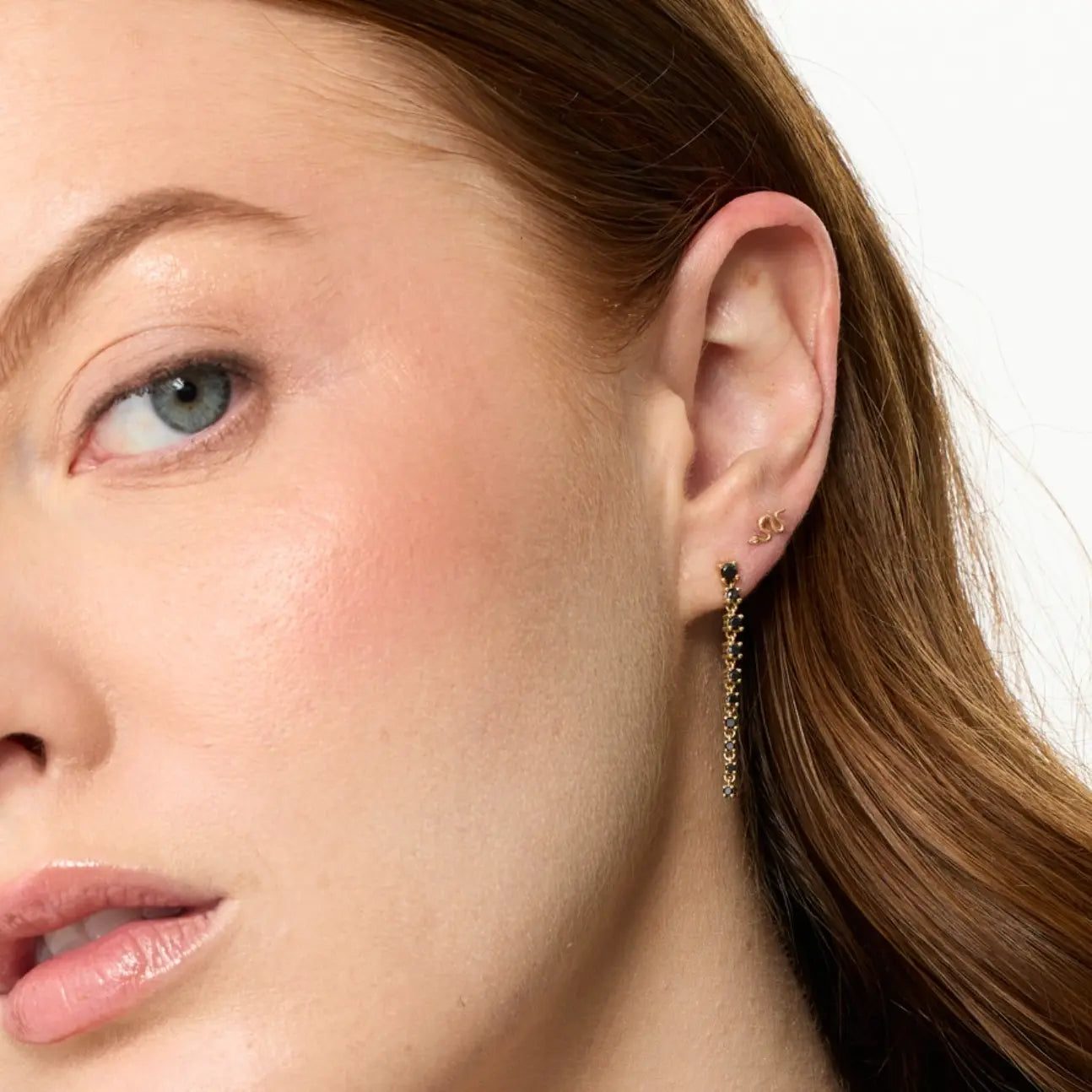 Close-up of a woman's ear with an earring on a white background