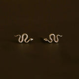pair of gold snake earrings on a brownish green background