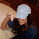 Woman wearing a light blue cap with 'ROCK NERD' logo, sitting at a table.