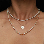 Close-up of a person wearing multiple pearl necklaces against a black background