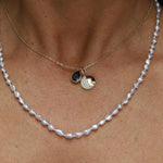 Pearl necklace with gold pendant on a person's neck