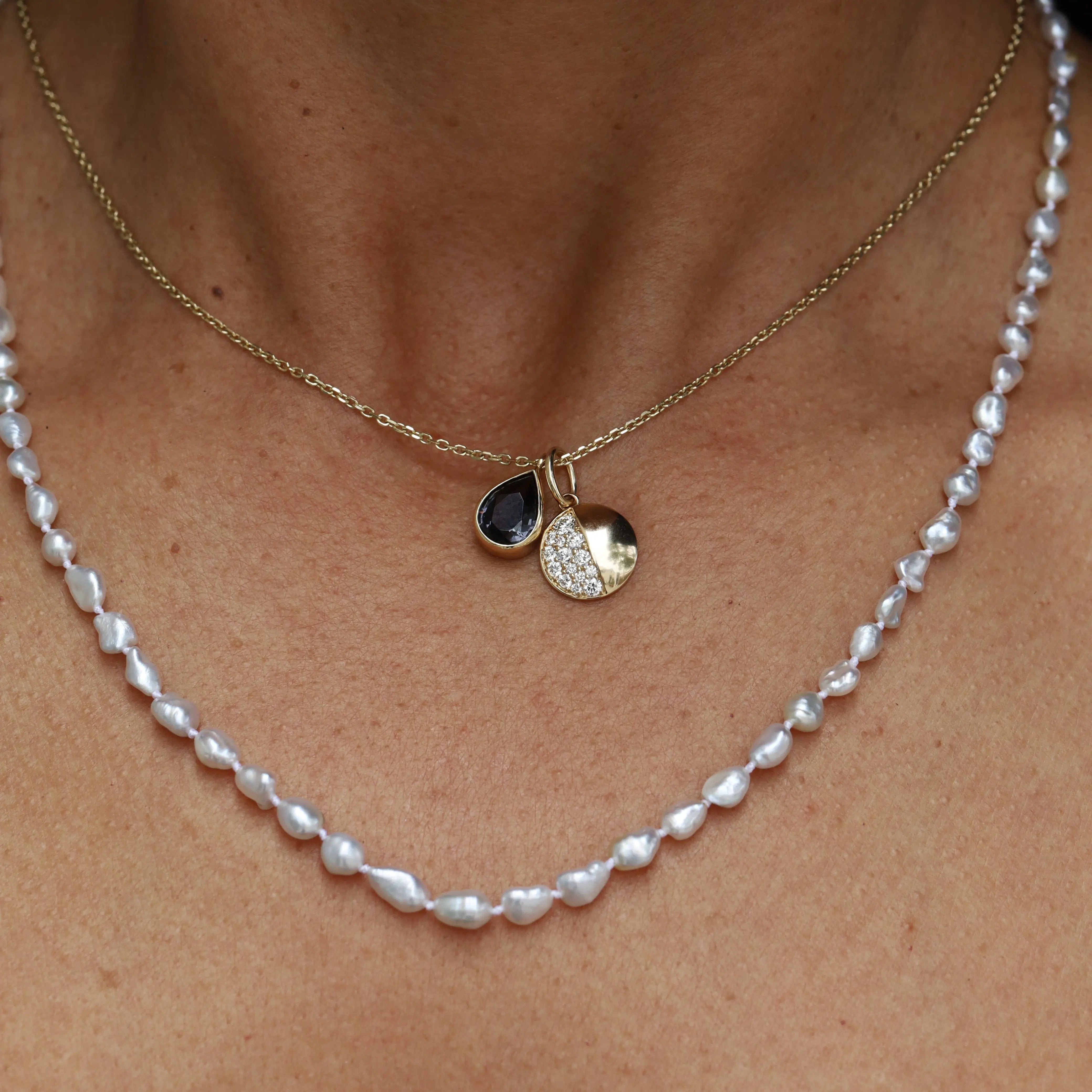 Pearl necklace with gold pendant on a person's neck
