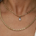 Gold chain necklace with a pearl pendant on a person's neck