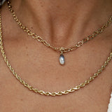 Gold chain necklace with a pearl pendant on a person's neck